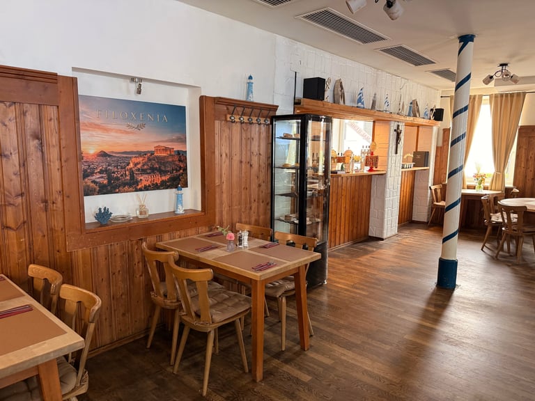 Wooden furniture showroom displaying dining tables, chairs, and cabinets with warm wood tones and landscape artwork on walls