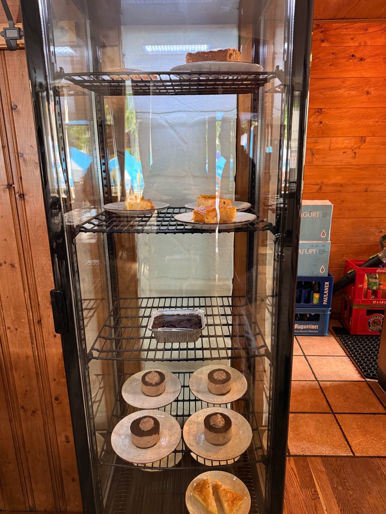 Glass bakery display case with shelves containing baked goods including bread, pastries, and pies on white plates